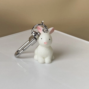 Close-up of a 3D white resin rabbit charm with a silver metal keychain clip