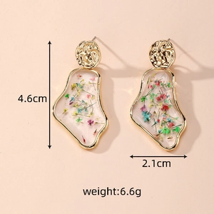 Detailed view of handmade clear resin earrings with colorful dried flowers and gold frame