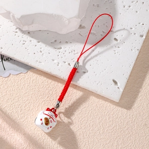 Macro shot of Japanese Maneki Neko lucky cat pendant with red woven cord on stone