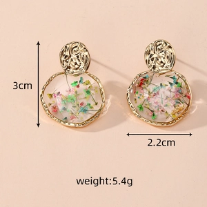 Detail view of round resin earrings with colorful dried flowers and gold metal tops