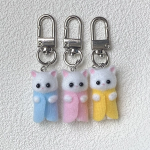 Detailed close-up of cute flocked cat keychains in blue, pink, and yellow colors