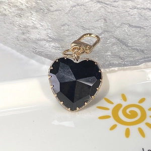 Detail of a black faceted heart pendant with golden metal trim and lobster clasp