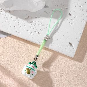 Close-up of a white lucky cat charm with a green cord on a white textured stone base
