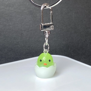 Detailed close-up of a cute green chick in eggshell keychain with silver metal clasp