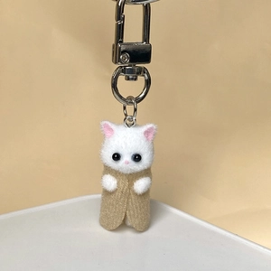 Close-up of a cute white flocked kitten keychain with a khaki shawl and silver metal clasp