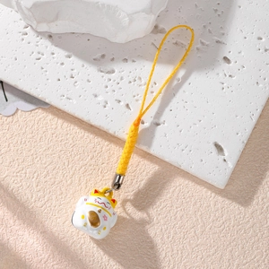 Detail of a white Maneki-neko lucky cat bell charm with yellow braided strap