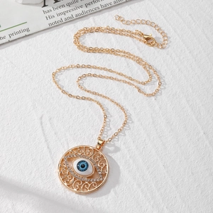 Collier vintage avec pendentif œil de protection doré et cristaux sur fond blanc