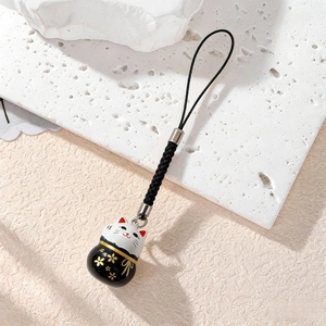 Detailed close-up of a Japanese lucky cat charm with black glaze and golden cherry blossoms