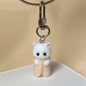 Close-up of a cute handmade white flocked cat plush keychain in a beige felt burrito wrap