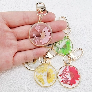 Handmade resin dried flower keychain with gold clasp in pink, green, and yellow hues