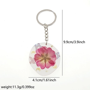 Nahaufnahme vom Schlüsselanhänger mit rosa Trockenblume, Schmetterling und Silberring