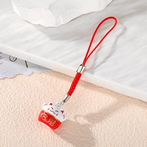 Detailed view of Maneki Neko lucky cat charm with red woven cord and gold lettering