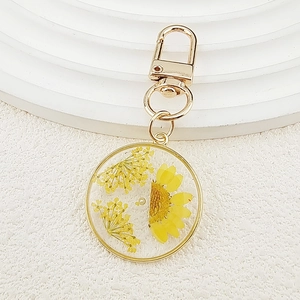 Macro shot of circular resin keychain with dried yellow sunflowers and gold metal clip