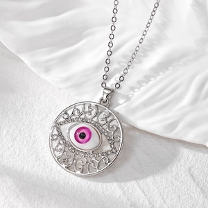 Vue macro du pendentif œil maléfique argenté avec iris rose et cristaux blancs brillants