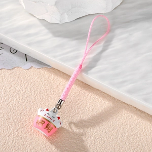 Close-up of pink Maneki-neko cat charm with golden Fortune text and braided cord