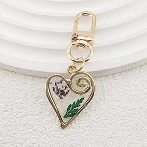 Creative heart-shaped keychain with purple dried flowers and green leaf in resin