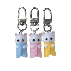 Three cute flocked cat keychains in pink, blue and yellow with colorful plush capes