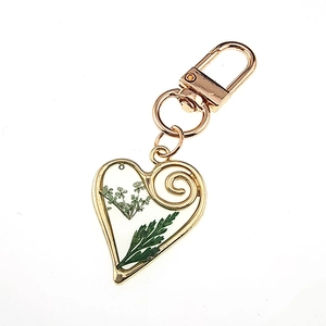 Macro shot of heart-shaped resin keychain with real white flowers and green leaves