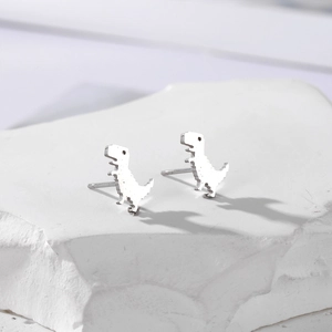 Minimalist silver dinosaur stud earrings made of stainless steel on a white stone background
