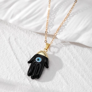 Detail of Hamsa Hand pendant with Evil Eye center and gold cross chain jewelry