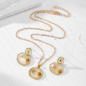 Sieradenset met madeliefjes hars met gouden ketting en oorbellen op witte ondergrond