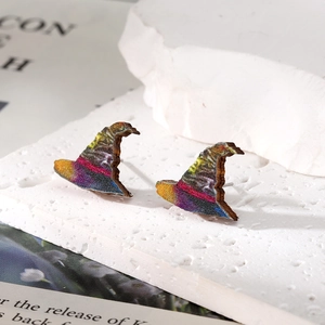 Macro shot of witch hat earrings with colorful glitter print on wooden base