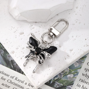 Detail of silver crystal butterfly keychain with black faceted gemstones on stone background