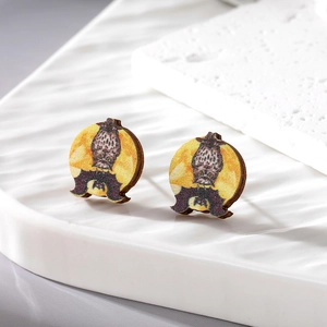 Macro detail of wooden Halloween earrings with owl and moon print on ceramic base