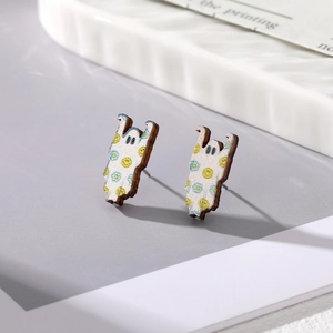 Detail of wooden ghost earrings with colorful dot print on a stylish white ceramic tray