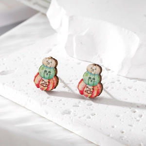 Close-up of stacked pumpkin earrings with facial expressions on white textured surface