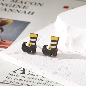 Macro shot of striped Halloween witch boot wooden earrings on white stone stand