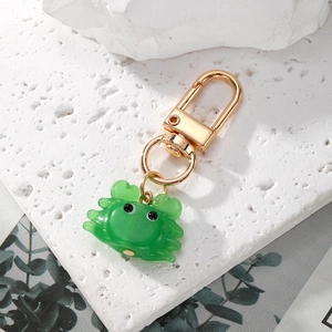 Mignon porte-clés crabe vert avec fermoir mousqueton doré sur un socle en pierre