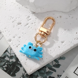Pendentif crabe en verre bleu ciel avec fermoir doré sur une pierre blanche texturée