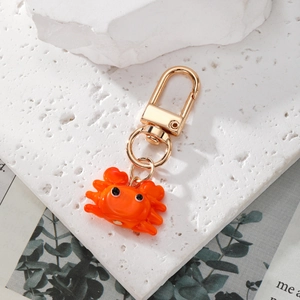 Détail d'un porte-clés crabe orange en résine avec un fermoir en métal doré brillant