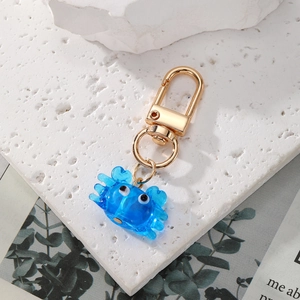 Détail d'un pendentif crabe bleu avec fermoir mousqueton doré sur pierre blanche