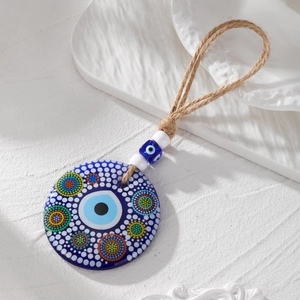 Detailed macro of large blue acrylic Evil Eye pendant with colorful dots and jute rope