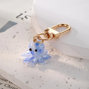 Macro shot of blue and white glass octopus pendant with a rotating golden metal hook