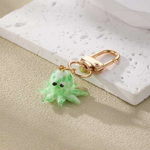 Detailed macro view of a green and white glass octopus keychain with a golden metal clasp