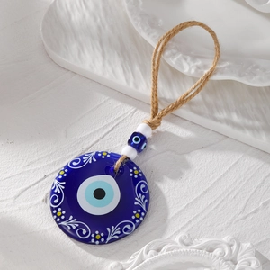 Detail of blue evil eye wall hanging with white vine patterns and rustic hemp rope hanger