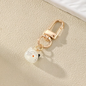 Detail eines süßen Katzen-Schlüsselanhängers aus weißem Harz mit goldenem Karabiner