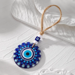 Detail shot of blue Evil Eye acrylic pendant with tribal motifs on white ceramic plate