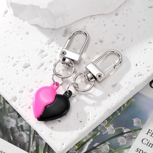 Dettaglio di portachiavi a forma di cuore diviso in rosa e nero con ganci argentati
