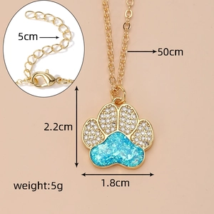 Detail of gold dog paw pendant with blue opal center and white cubic zirconia accents