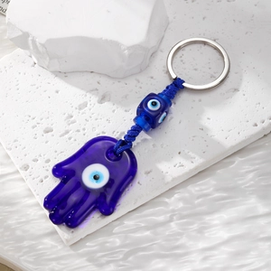 Hamsa Hand and Evil Eye glass keychain with blue beads on a decorative white stone