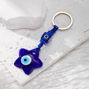 Blue Evil Eye star-shaped keychain pendant on white stone surface with water ripples