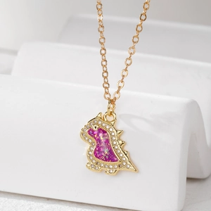 Close-up of golden dinosaur necklace with purple opal resin and sparkling crystal bezel