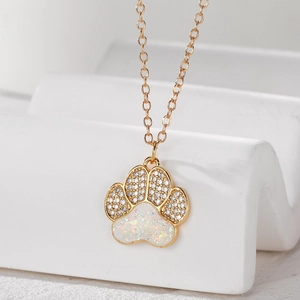 Close-up of gold cat paw necklace with white zircon and iridescent opal inlay details