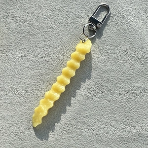 Macro shot of realistic crinkle-cut French fry keychain with a silver metal clasp