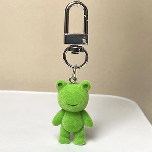 Gros plan d'un mignon porte-clés ours floqué vert avec un fermoir pivotant en métal argenté