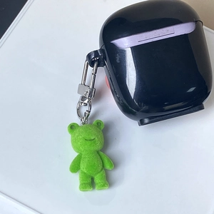 Mignon porte-clés ours floqué vert accroché à un étui d'écouteurs noir brillant